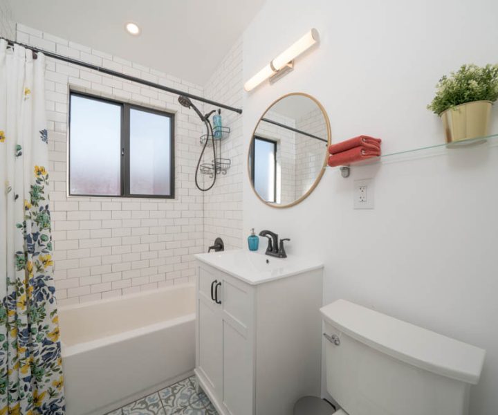 A small, inviting bathroom with a floral shower curtain, subway tiles, and a contemporary sink vanity, providing a fresh and clean look.