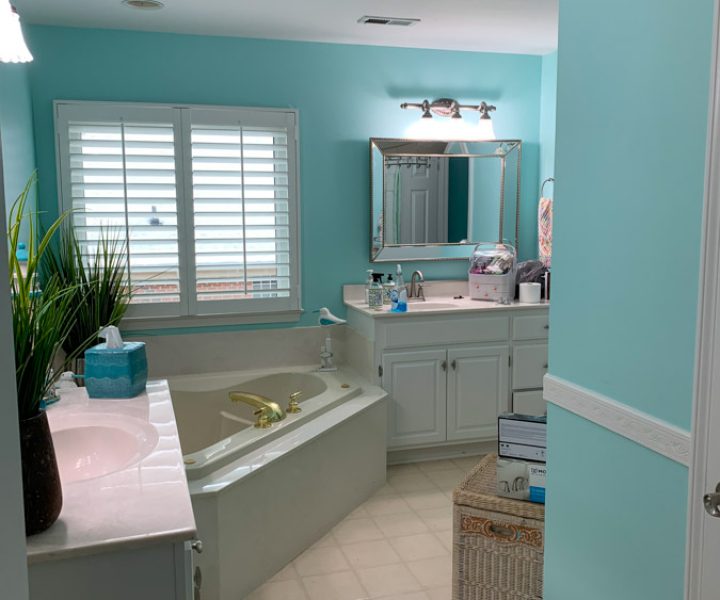 A spacious bathroom with turquoise walls, white cabinetry, and modern fixtures, reflecting the handyman’s expertise in bathroom remodeling and home repairs.